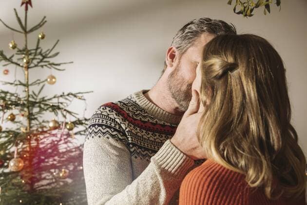 Happy couple standing in front of Christmas tree, kissing under mistletoe model released Symbolfoto property released  MFF002819
