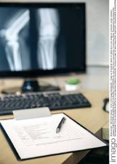 Close-up of medical report on table and x-ray image on computer screen property released  DAPF000058
