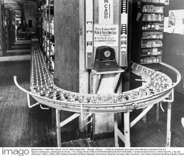 Chicago, Illinois: c. 1955 An employee time card clock behind a conveyor line in a factory warehouse. Underwood Archives The Image Works xUnderwoodxArchives 1-Work-Fact-Mi_1