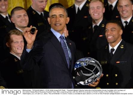 President Barack Obama looks at a championship ring as he poses with members of the United States Naval Academy Football Team after presenting them with the 2015 Commander-in-Chief?s Trophy, at the White House in Washington, D.C. on April 27, 2016. The Commander-in-Chief s Trophy is awarded to each season s winner of the American college football triangular series among the teams of the U.S. Military Academy, the U.S. Naval Academy, and U.S. Air Force Academy.  WAP20160427335 KEVINxDIETSCH