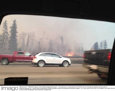 A house burns in downtown Fort McMurray as evacuating vehicles drive south on Alberta Highway 63. 04 05 2016 PANORAMIC GREGHALINDA 