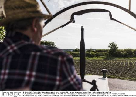 Farmer on tractor next to field model released Symbolfoto  UUF007334