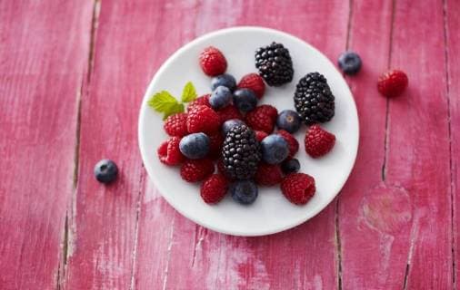 Dish of different wild berries on pink wood  KSWF001758