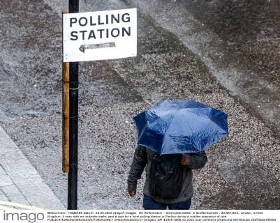 EU-Referendum - Schmuddelwetter in Großbritannien . 23 06 2016. London, United Kingdom. A man with an umbrella walks past a sign for a local polling station in Pimlico during a sudden downpour of rain.  xPetexMaclainex xi-Imagesx IIM-12955-0008