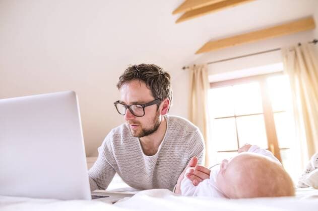 Father with baby lying on bed using laptop model released Symbolfoto property released  HAPF000479