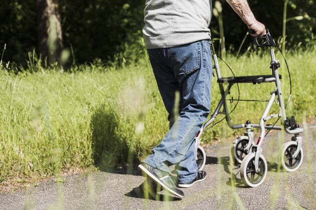 Back view of senior man strolling with wheeled walker in nature model released Symbolfoto  UUF007584