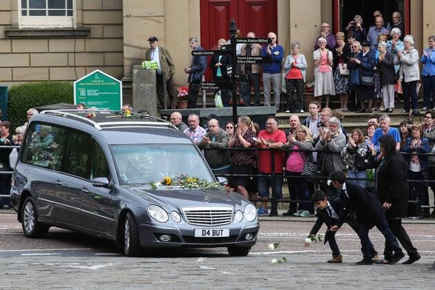 Trauerfeier für Jo Cox in Batley July 15, 2016 - Batley, West Yorkshire, UK - Batley, UK. A family puts down flowers in front of Jo Cox s funeral cortege as it passes through her hometown of Batley, West Yorkshire. The Labour MP was stabbed and shot in the street as she left her constituency surgery last month. Thomas Mair was arrested in connection with the murder and is set to face trial this year. Batley UK  - ZUMAl94_