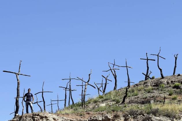 IMAGO Nature: Unsere Erde, Klimawandel, Waldbrände Artist Marc Sellares (L) poses next to his artistic installation in a burnt forest in El Bruc, Barcelona, northeastern Spain, 26 July 2016. The artist began to transform the dead tries in 1,293 crosses one year ago as a mourning ritual . Each cross symbolizes each hectare destroyed. EFE Alberto Estevez Artistic installation in a burnt forest !ACHTUNG: NUR REDAKTIONELLE NUTZUNG!  20160726-636051415365720112