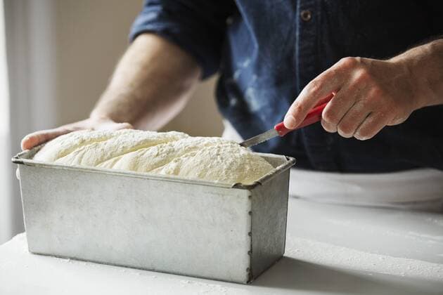 Close up of a baker cutting bread dough in a baking tin. Close up of a baker cutting bread dough in a baking tin.  21819