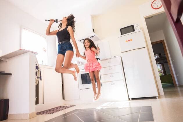 Playful teenage girl with her little sister in kitchen pretending to sing into microphone model released Symbolfoto property released  SIPF000632