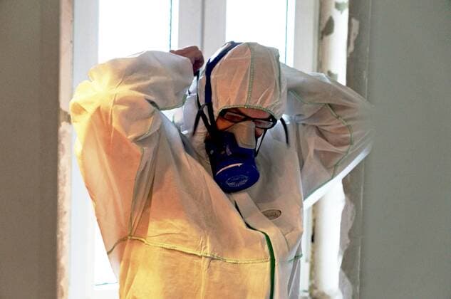 Asbestsanierung in einer Bremer Wohnung, in der Badezimmerfliesen mit Asbestkleber belastet sind. Bad und WC werden durch einen Staubvorhang luftdicht abgeschlossen. Ein Spezialsauger erzeugt Unterdruck und saugt nach dem Abstemmen der Fliesen den Asbeststaub auf.