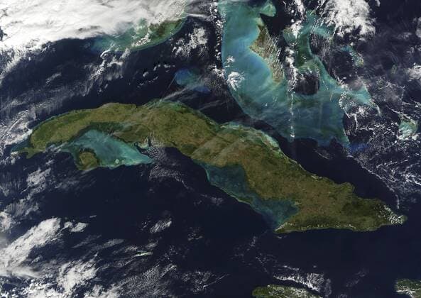 January 1, 2010 - Satellite view of Cuba showing wispy clouds and some fading jet contrails. The waters are jewel-like: turquoise, bright blue, and emerald green near the islands, as well as the deeper blue of the Gulf of Mexico (top left) and the Atlantic Ocean (right). The brighter colors surrounding the Bahamas (the islands north of Cuba) are caused by the relatively shallow waters over the Little and Great Bahama Banks. The brightly-colored waters around Cuba and Florida™s tip (visible at the top of the image) could be a consequence of shallow waters, but could also be colored by a larger presence of microscopic marine organisms, such as algae and phytoplankton, which lend a darker-green tinge to the water.  Copyright: StocktrekxImages stk203158s