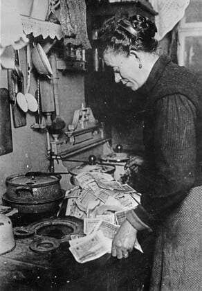 Inflation. In Germany after the last war, it was possible to pay 50 million dollars for a nickel cup of coffee, and 35 million dollars for a $35 suit of clothes. This Berlin woman, realizing that fuel costs money, is starting the morning fire with marks not worth the paper they are printed on WHA  !ACHTUNG AUFNAHMEDATUM GESCHÄTZT! Copyright: WHA UnitedArchivesWHA_066_0056