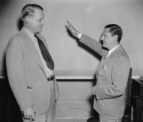 Called as the first witness before the Special House Committee investigating Un-American activities, John Metcalfe, former Chicago reporter but now an investigator for the committee, gives Chairman Martin Dies (right) a Nazi salute before taking the stand. Joining under the name of Helmut Oberwinder, Metcalfe related his experiences as a member of the German-American bund and charged the organization has a secret relationship with the Nazi government in Germany, WHA  !ACHTUNG AUFNAHMEDATUM GESCHÄTZT! Copyright: WHA UnitedArchivesWHA_066_0182