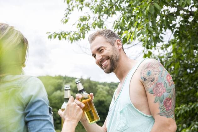 Smiling couple clinking beer bottles in the nature model released Symbolfoto  FMKF002810