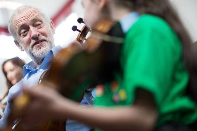 September 27, 2016 - Liverpool, Merseyside, UK - Liverpool , UK . Labour Party leader JEREMY CORBYN is shown how to play the violin by JESSICA KELLY (10) during a visit to Faith Primary School in Liverpool , where he listens to and then joins in with the school orchestra Liverpool UK  - ZUMAl94_
