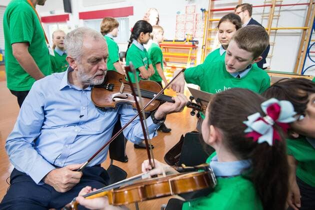 September 27, 2016 - Liverpool, Merseyside, UK - Liverpool , UK . Labour Party leader JEREMY CORBYN is shown how to play the violin by JESSICA KELLY (10) during a visit to Faith Primary School in Liverpool , where he listens to and then joins in with the school orchestra Liverpool UK  - ZUMAl94_
