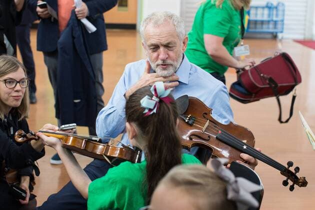 September 27, 2016 - Liverpool, Merseyside, UK - Liverpool , UK . Labour Party leader JEREMY CORBYN is shown how to play the violin by JESSICA KELLY (10) during a visit to Faith Primary School in Liverpool , where he listens to and then joins in with the school orchestra Liverpool UK  - ZUMAl94_