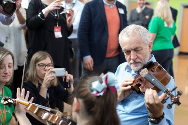 September 27, 2016 - Liverpool, Merseyside, UK - Liverpool , UK . Labour Party leader JEREMY CORBYN is shown how to play the violin by JESSICA KELLY (10) during a visit to Faith Primary School in Liverpool , where he listens to and then joins in with the school orchestra Liverpool UK  - ZUMAl94_