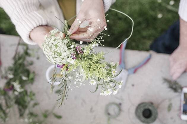 Close up of a woman, standing in a garden, making a flower wreath. Close up of a woman, standing in a garden, making a flower wreath.  22452