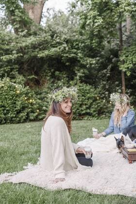 Two smiling women with a flower wreaths in their hair sitting in a garden. Two smiling women with a flower wreaths in their hair sitting in a garden.  22472