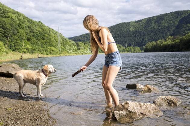 Young woman playing with her dog in a lake model released Symbolfoto property released  FMKF002796