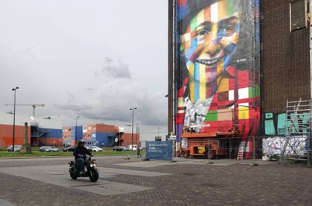 The Netherlands, Amsterdam. The famous Brazilian street artist Eduardo Kobra realizes this week a monumental portrait of Anne Frank. 26 september 2016, Photo: Katrien Mulder Hollandse Hoogte Nederland, Amsterdam, Amsterdam Noord, NDSM Terrein, wereldberoende Braziliaanse streetartist Eduardo Kobra realiseert deze week een monumentaal portret van Anne Frank op de zuidelijke buitenmuur van de loods op de hoek van de MS van Riemsdijkweg, en de Tt Neveritaweg, famous Brazilian street artist Eduardo Kobra (l) realizes this week a monumental portrait of Anne Frank 26 september 2016, foto: Katrien Mulder  59396750