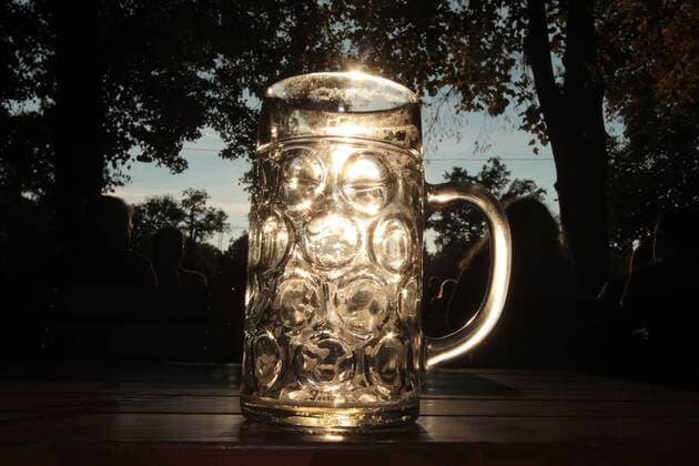spätsommerliche Temperaturen und schönster Sonnenschein lockten viele Sonnenhungrige in den Biergarten Königlicher Hirschgarten in München, Bayern, Deutschland. Mass Bier im Gegenlicht der Nachmittagssonne