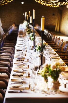 A wedding venue decorated for a party, with fairy lights and a long table set for dinner. A wedding venue decorated for a party, with fairy lights and a long table set for dinner.  24078