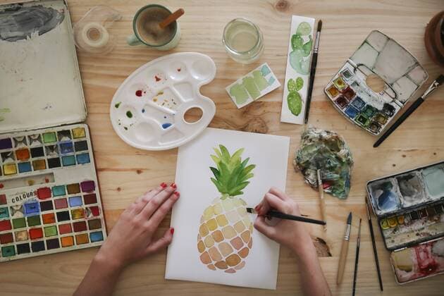 Woman s hand painting aquarelle of a pineapple on desk in her studio model released Symbolfoto property released  RTBF00434