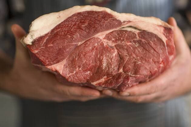 Butcher holding piece of raw meat model released Symbolfoto property released  ZEF010291