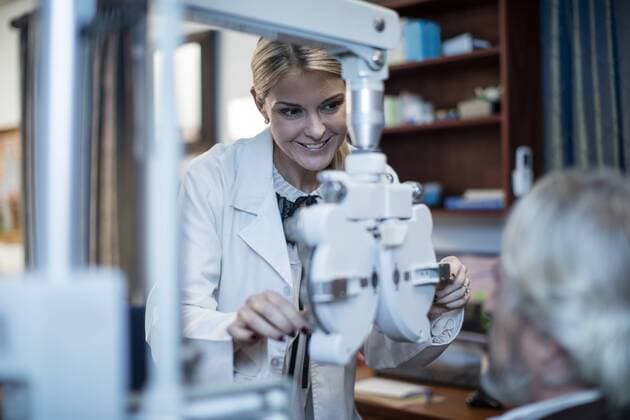 Female optometrist doing eye test with patient model released Symbolfoto property released  ZEF10572