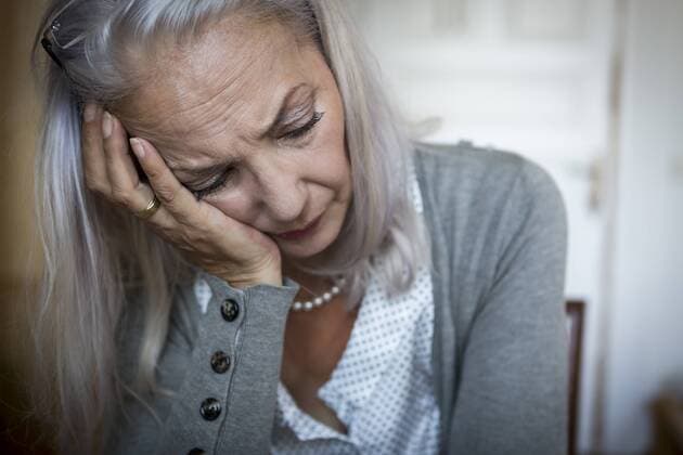 IMAGO Creative: Gesundheit, Demenz Portrait of sad woman with head in her hand at home model released Symbolfoto property released  JUNF00691
