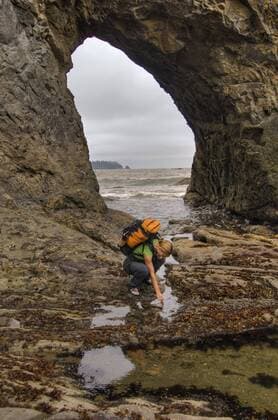 IMAGO Creative: UN Welt-Habitat-Tag am 3. Oktober USA, Washington, Olympic National Park. A female backpacker enjoys the tidepools in front of a rock arch near Rialto Beach. (MR)  Copyright: xDavidxSvilarx xDanitaxDelimont US48 DSV0103