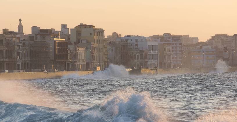 Buildings along The Malecon bathed in soft evening sunlight with large waves crashing against the sea wall, The Malecon, Havana, Cuba, West Indies, Caribbean, Central America Copyright: LeexFrost 321-5508