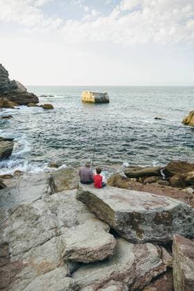 Grandfather and grandson fishing together at the sea sitting on rock model released Symbolfoto  DAPF00428
