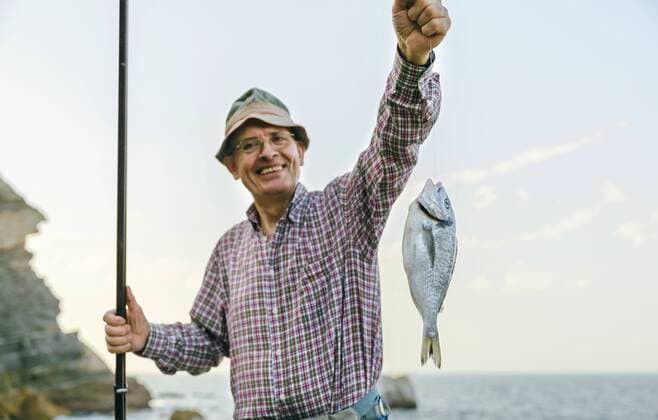 Happy senior man holding fish on fishing line model released Symbolfoto  DAPF00441