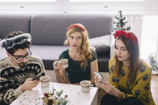 Annoyed young woman sitting between her friends looking at her smartphones model released Symbolfoto  LCUF00068