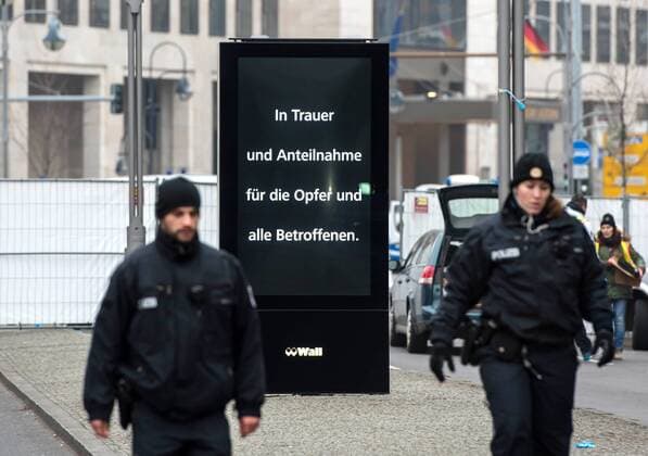 Anschlag in Berlin - Trauer um die Opfer auf dem Breitscheidplatz Berliner Polizisten stehen am Dienstag (20.12.16) in der Naehe der der Kaiser-Wilhelm-Gedaechtniskirche vor dem abgesperrten Weihnachtsmarkt, in den am Montagabend ein LKW gefahren war. Zwoelf Menschen kamen dabei ums Leben, 48 wurden zum Teil schwer verletzt. Die Werbefirma Wall hat ihre elektronische Werbetafel neben dem Tatort mit einem Trauerspruch versehen. Die Polizei sprach am Dienstagmorgen von einem vermutlich terroristischen Anschlag . Der Generalbundesanwalt leitete nach Angaben von Justizminister Maas ein Ermittlungsverfahren ein. Trauer um Anschlagsopfer auf Berliner Weihnachtsmarkt Copyright: epd-bild ChristianxDitsch EDITORIAL USE ONLY