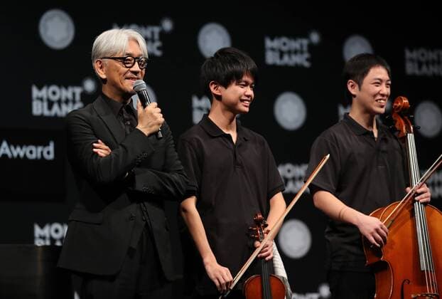 December 21, 2016, Tokyo, Japan - Japanese composer Ryuichi Sakamoto (L), a member of the Yellow Magic Orchestra (YMO) smiles with young musicians after he received Montblanc de la Culture Arts Patronage Award in Tokyo on Wednesday, December 21, 2016. Sakamoto played his screen music Merry Christmas Mr. Lawrence with young musicians.  (lwxa007006)