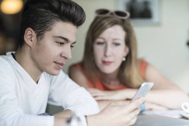 IMAGO Creative: Gesellschaft, Integration Teenage boy using cell phone with woman in background model released Symbolfoto  TAMF00888