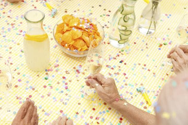 Celebrating senior sitting at table with infused water, champagne and potato chips model released Symbolfoto property released  MFRF00784