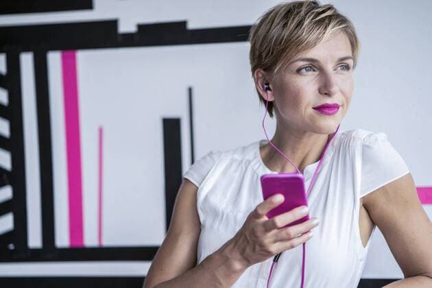 Woman in modern office listening to music on smartphone model released Symbolfoto property released  RIBF00640