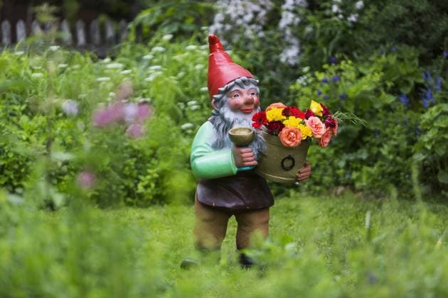 DEU, Deutschland, Muensingen, 11.06.2016: Ein ueberdimensionaler Gartenzwerg, eher schon ein Gartenriesse, steht mit Blumenschale in einem Garten. Â