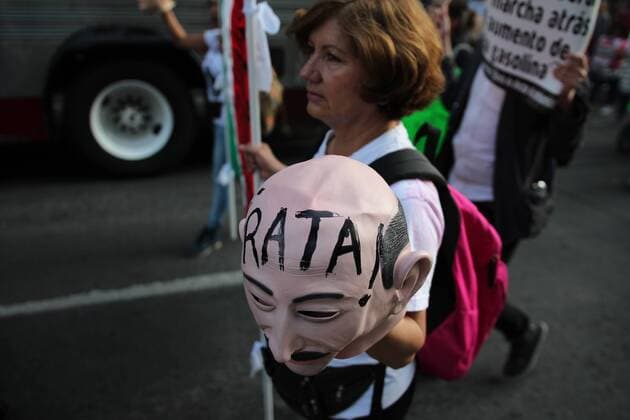 January 9, 2017 - Mexico City, Mexico - A woman in Mexico city on 9 January 2017, holds a cartel with a plastic face of the ex president Salinas de Gortari with the word in Spanish saying stop as the relation against fuel prices in Mexico. Largely peaceful protests against the fuel price increases continued nationwide in Mexico, and looting seen last week largely subsided. The protests have left hundreds of businesses looted and more than 1,500 detained. Mexico City Mexico  - ZUMAn230 20170109_zaa_n230_048