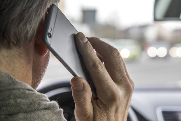 Mann, Autofahrer, benutzt ein Handy, während der Fahrt, ohne Freisprecheinrichtung,