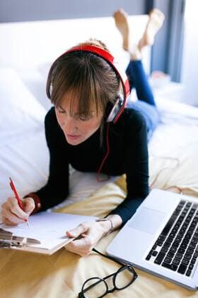 Young woman lying on bed writing on clipboard model released Symbolfoto property released  VABF01128