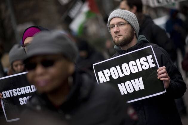 Gedenkmarsch Kolonialgeschichte DEU, Deutschland, Germany, Berlin, 25.02.2017 Demonstranten mit Plakat Apologise now, Entschuldigung sofort, beim 11. Gedenkmarsch zur Erinnerung an die afrikanischen Opfer von Versklavung, Kolonialismus und rassistischer Gewalt vom Komitee fuer ein afrikanisches Denkmal in Berlin und afrikanischer Vereine in Berlin. Dieser Gedenkmarsch wurde ins Leben gerufen, um der Forderung nach Anerkennung der Verbrechen gegen Schwarze Menschen und Menschen afrikanischer Herkunft Nachdruck zu verleihen. Anlass ist die Berliner Afrika-Konferenz von 1884 - 1885, auf der Afrika vor 130 Jahren unter den europaeischen Kolonialmaechten aufgeteilt wurde. Mehr als 30 Millionen Afrikanerinnen und Afrikaner wurden Opfer von Versklavung und kolonialen Verbrechen gegen die Menschlichkeit. Die von Deutschland an den Herero und Nama begangenen Voelkermorde in Namibia und die Kriegs