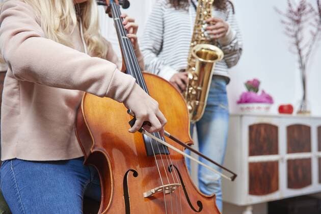 Two girls playing cello and saxophone together model released Symbolfoto property released  RHF01809