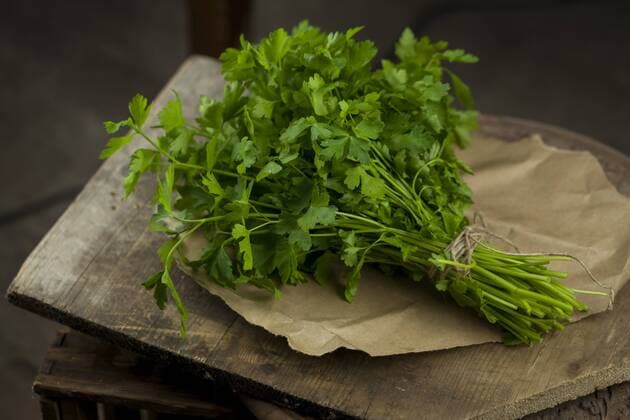 Bunch of flat leaf parsley on brown paper and wood  JUNF00818